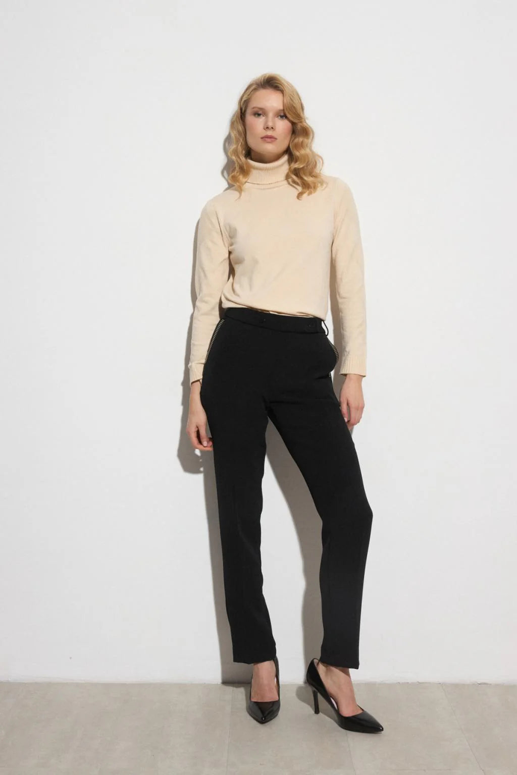 Model wearing Bariloche Luncaria black straight-leg smart trousers with studded pocket detail.