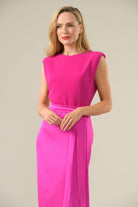 Woman wearing a Caroline Kilkenny bright pink dress against a plain background