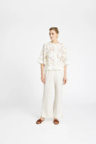Model wearing Gustav Grazia white embroidered lace shirt with wide-leg trousers