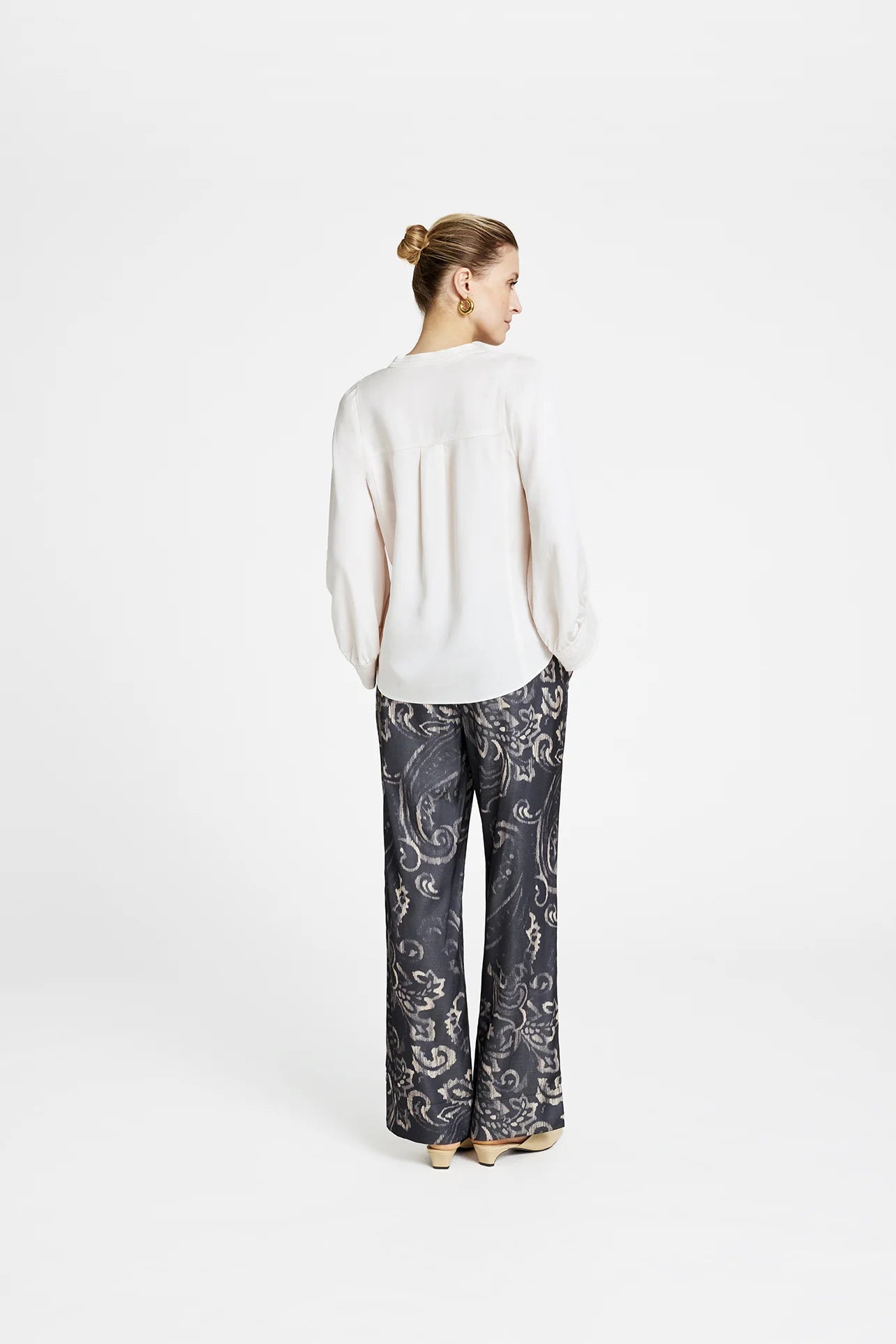 Rear view — Gustav Kaisa cream lyocell blouse styled with grey paisley wide-leg trousers and neutral mules.