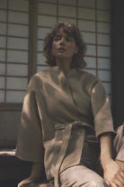 Gustav Dua camel cape style jacket worn by model, showing high collar and waist tie belt.
