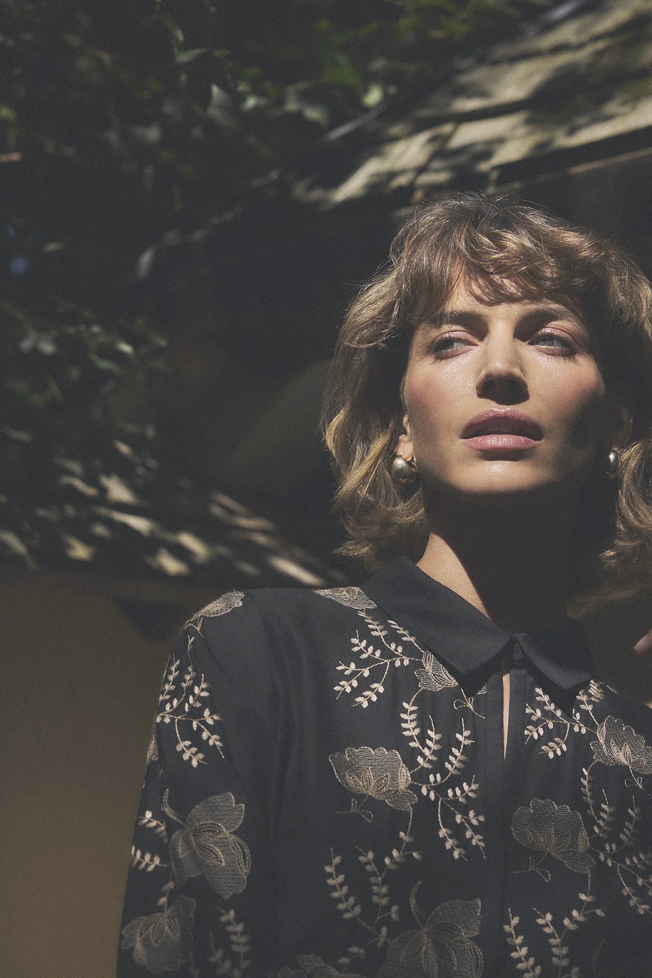 Gustav Bayanna black floral embroidered blouse worn by model, showing contrasting floral detailing and collared neckline.