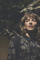 Gustav Bayanna black floral embroidered blouse worn by model, showing contrasting floral detailing and collared neckline.