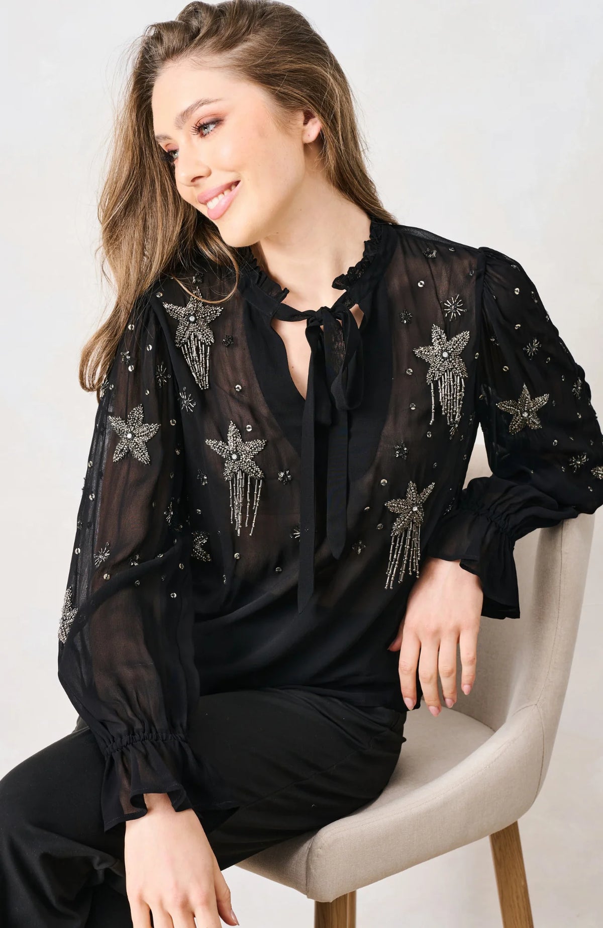 LHope & Ivy Elaris black beaded star mesh top with tie neckline – seated model view