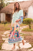 Woman walking outdoors in mint green printed kimono dress with blue and pink border