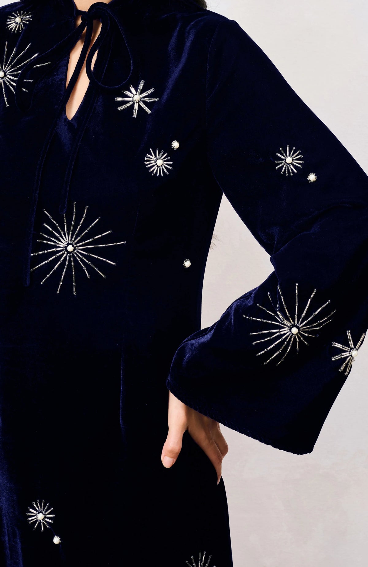 Close-up of Hope & Ivy Orelia navy velvet dress showing silver celestial starburst embellishments on the sleeve and bodice.