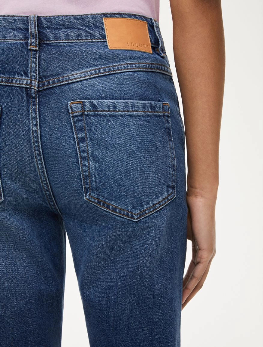 Close-up of red-stitched back pocket detail on women’s blue denim jeans