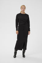 Full-length look of InWear black knot side top styled with a black midi skirt