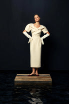 Model wearing Kameya Draped Shoulder Midi Dress in cream with statement neckline
