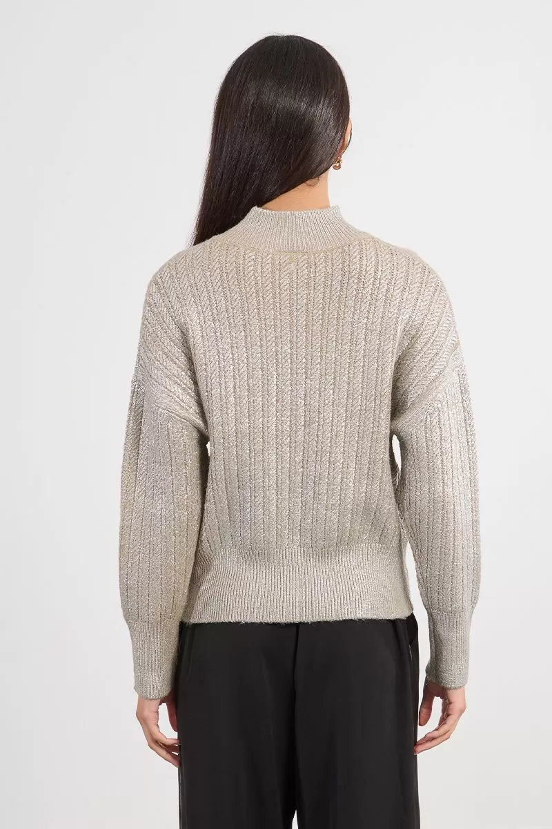 Back view of neutral Lili Sidonio cable knit jumper, worn with black trousers
