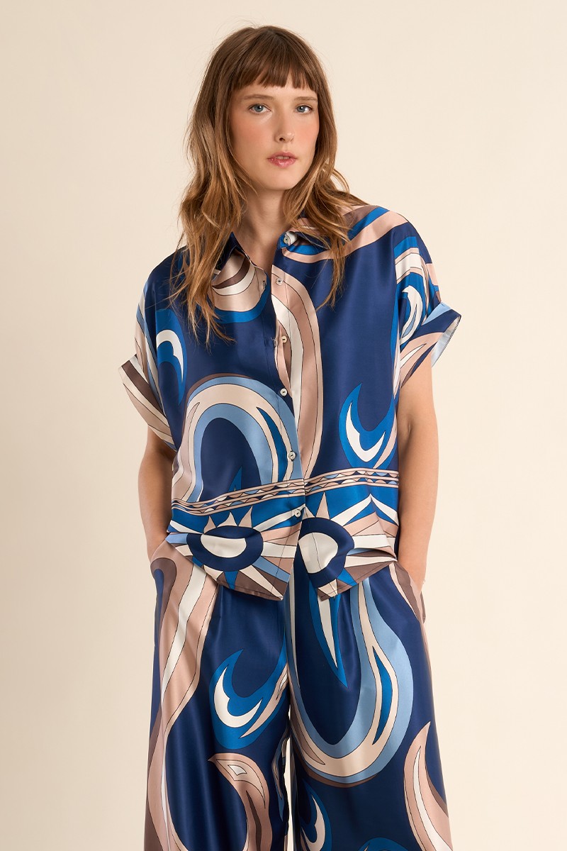 Molly Bracken silky graphic print blouse in blue styled with cream trousers