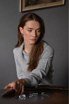 Model seated in Molly Bracken grey cozy cowl neck sequin sweater