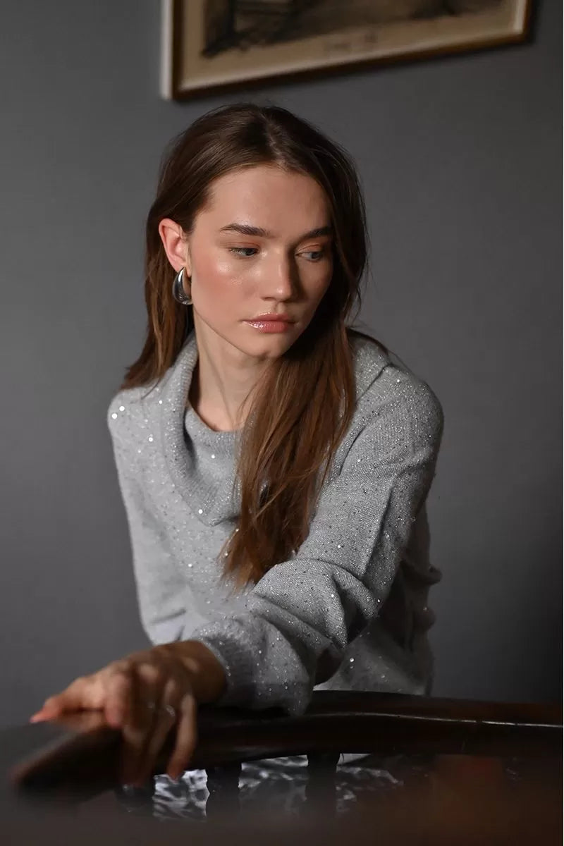 Model seated in Molly Bracken grey cozy cowl neck sequin sweater