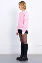 Side profile of Molly Bracken pink graphic textured knit jumper Styled with black boots 