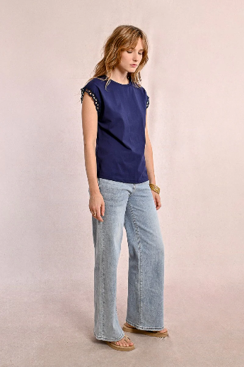 Model styling navy T-shirt with openwork sleeves and high-rise jeans.