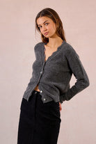 Side profile of Molly Bracken charcoal lace knit cardigan styled with black skirt.