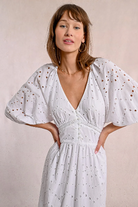 White midi dress with intricate broderie, V-neck, and subtle volume