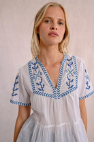 Close-up of embroidered detailing on the V-neckline and sleeves of cotton poplin blouse.