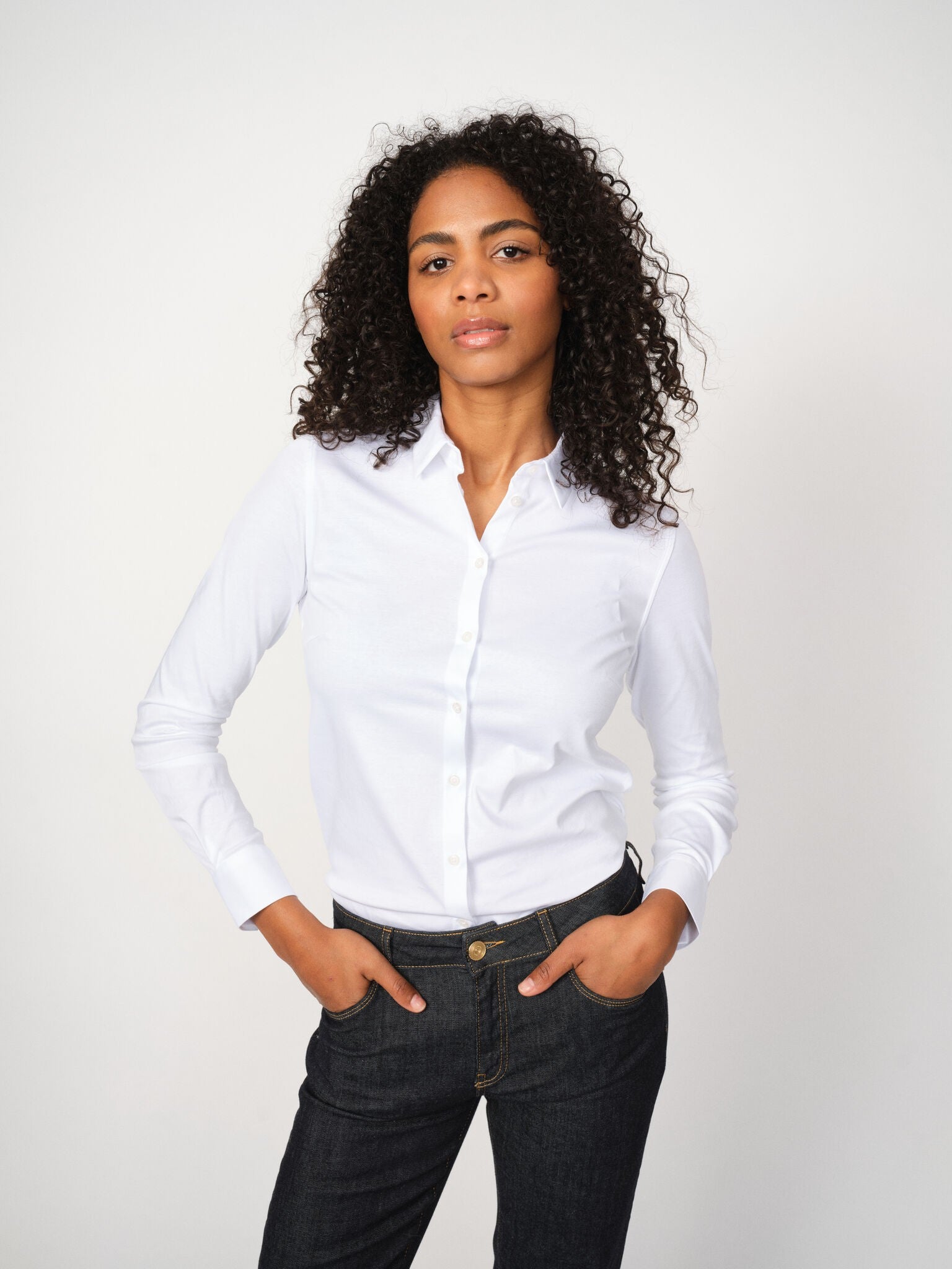 Woman wearing Mos Mosh Tina Jersey Shirt in white, styled with dark denim jeans.