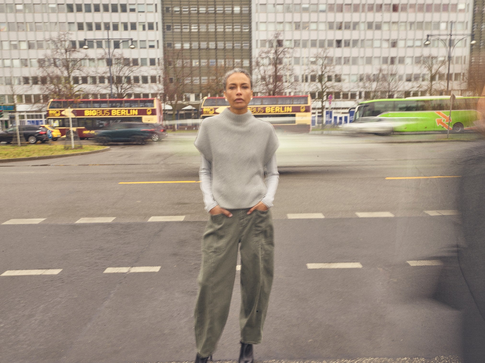 Model styling Mos Mosh grey sleeveless vest jumper over white shirt