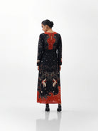 NOIB Aura Old Rose black printed maxi dress with orange-red back detail and patterned hem – rear model view.