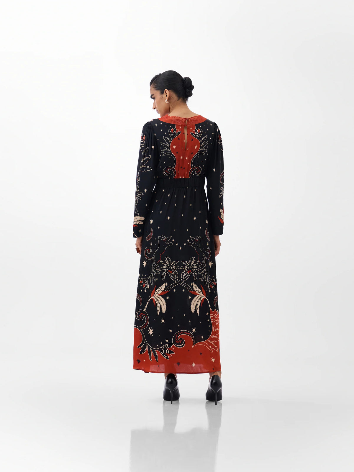 NOIB Aura Old Rose black printed maxi dress with orange-red back detail and patterned hem – rear model view.