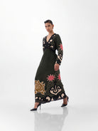 NOIB Aura green and black V-neck maxi dress with pink floral motifs and gold detailing – side model view.
