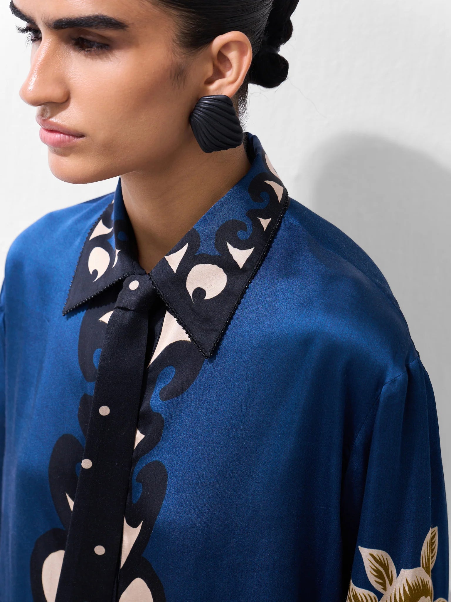 NOIB Iris blue ornamental floral shirt with dark printed collar and tie-neck detail – close-up model view.