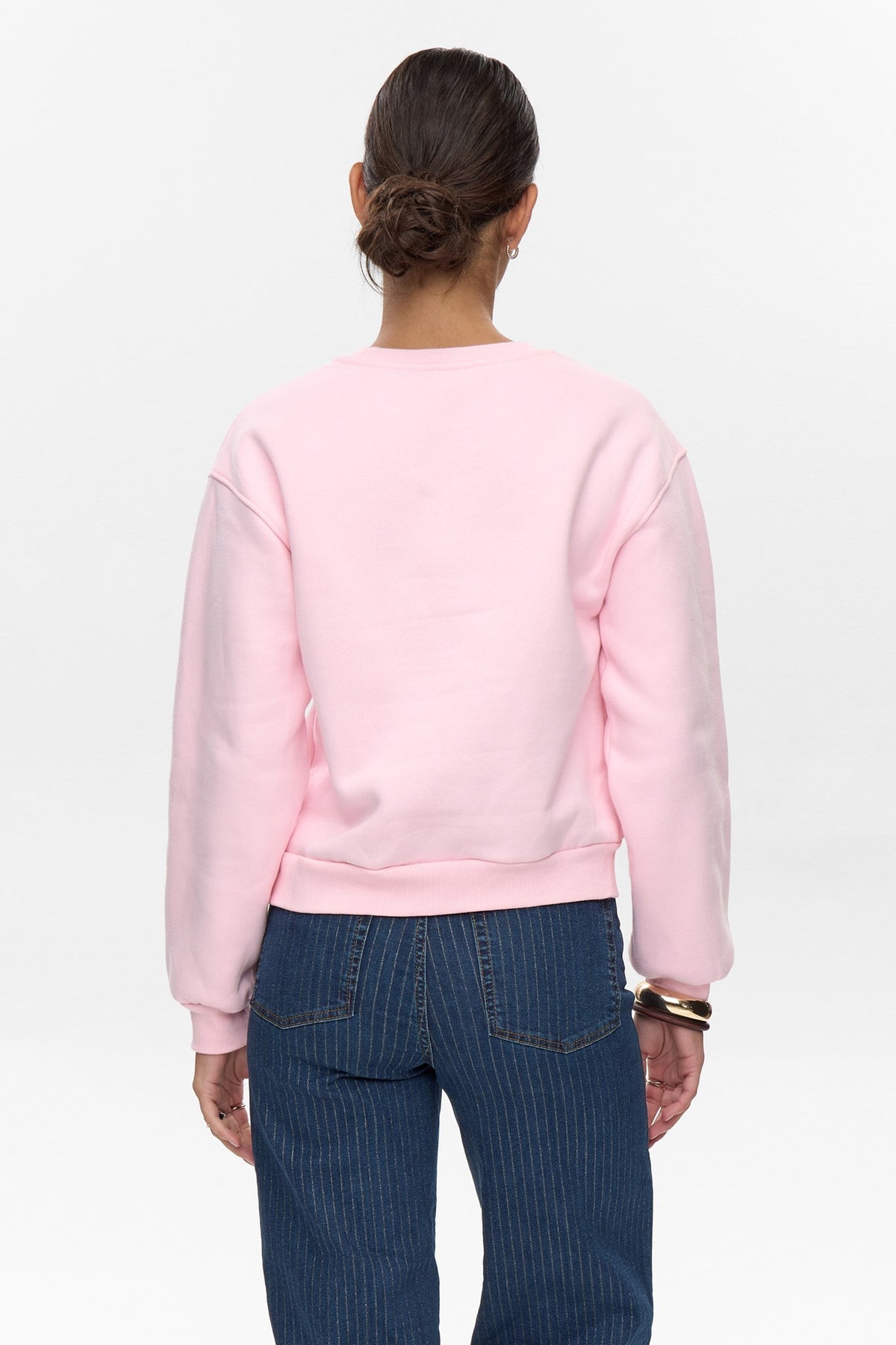 Back view of cherry blossom pink Numph sweatshirt styled with casual denim