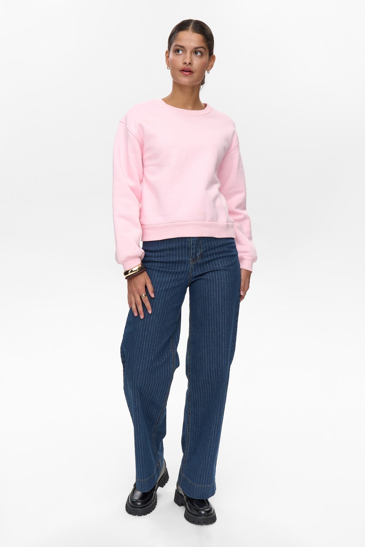Full-length front view of pink crew neck Numph jumper paired with jeans