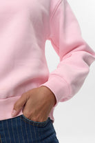 Side detail of Numph pink crew neck jumper showing ribbed cuff and hem finish
