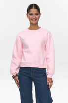 Front view of model wearing Numph cherry blossom pink crew neck sweater with relaxed fit and blue jeans