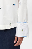 Mini floral and icon embroidery on Numph Nuchiro white cotton shirt sleeve.