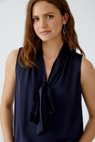 Close-up of model in navy satin work blouse with V-neck and tie detail