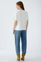 Back view of model wearing white Oui t-shirt with relaxed jeans and boots