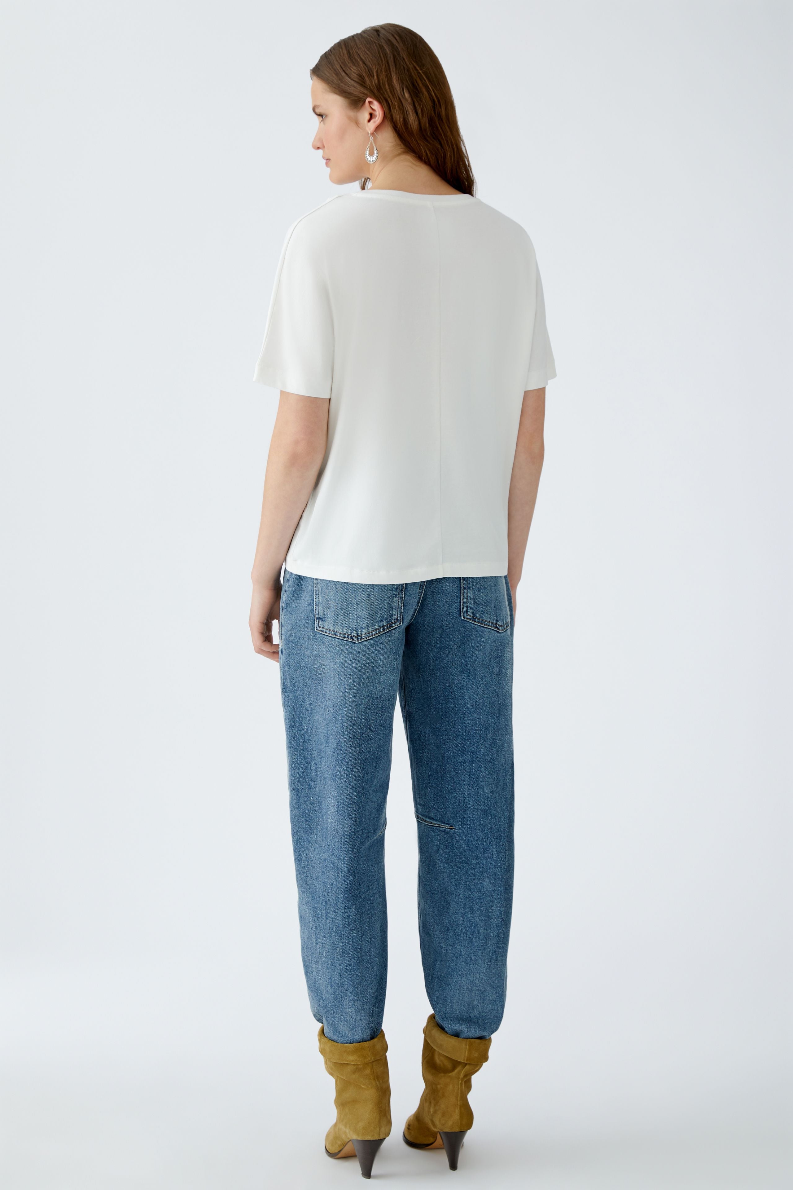Back view of model wearing white Oui t-shirt with relaxed jeans and boots