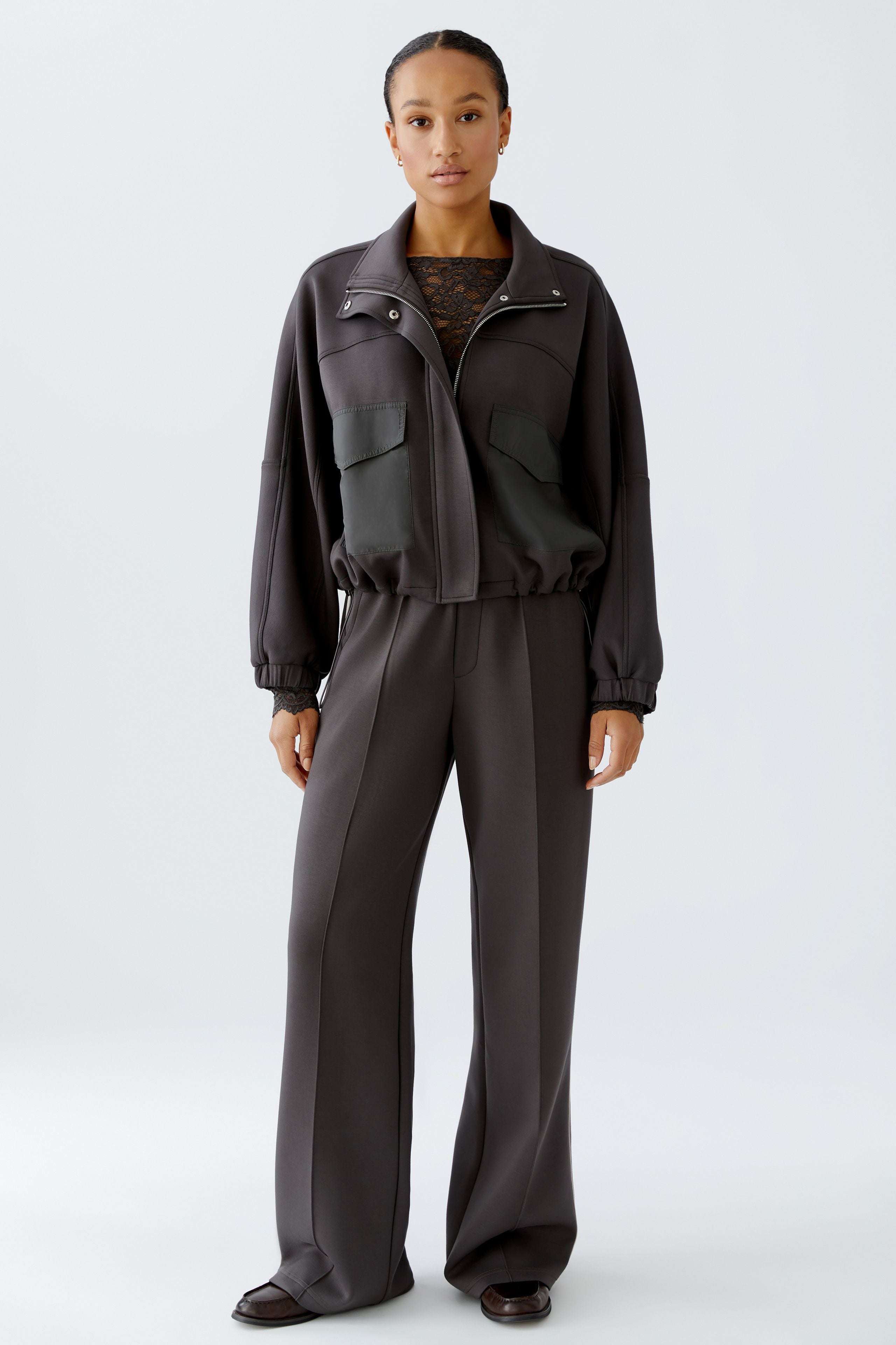 Full-length view of model in dark grey scuba jacket and trousers