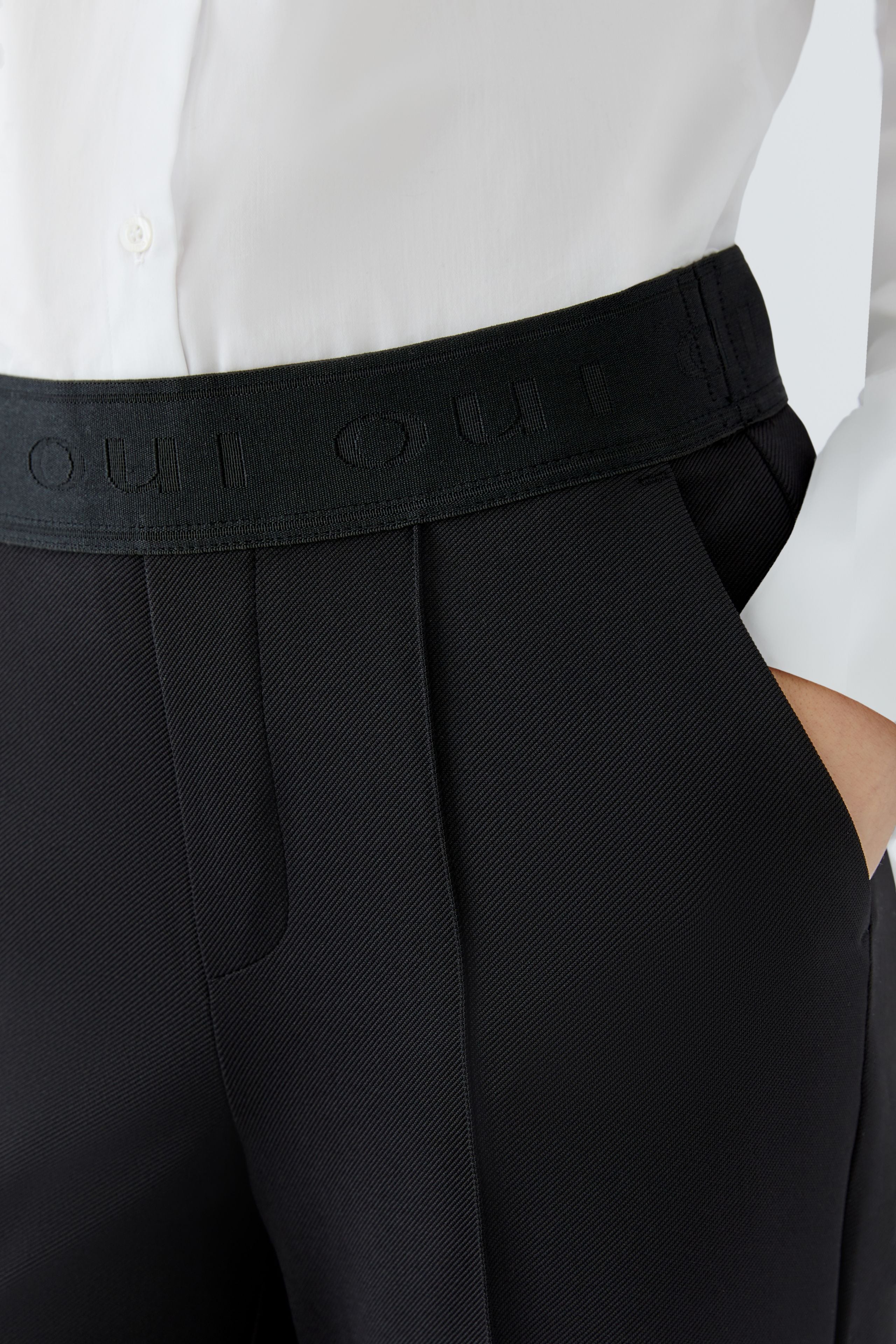 Oui NEYA black pull-on trousers with elasticated waistband, stitched crease and side pocket – detail view