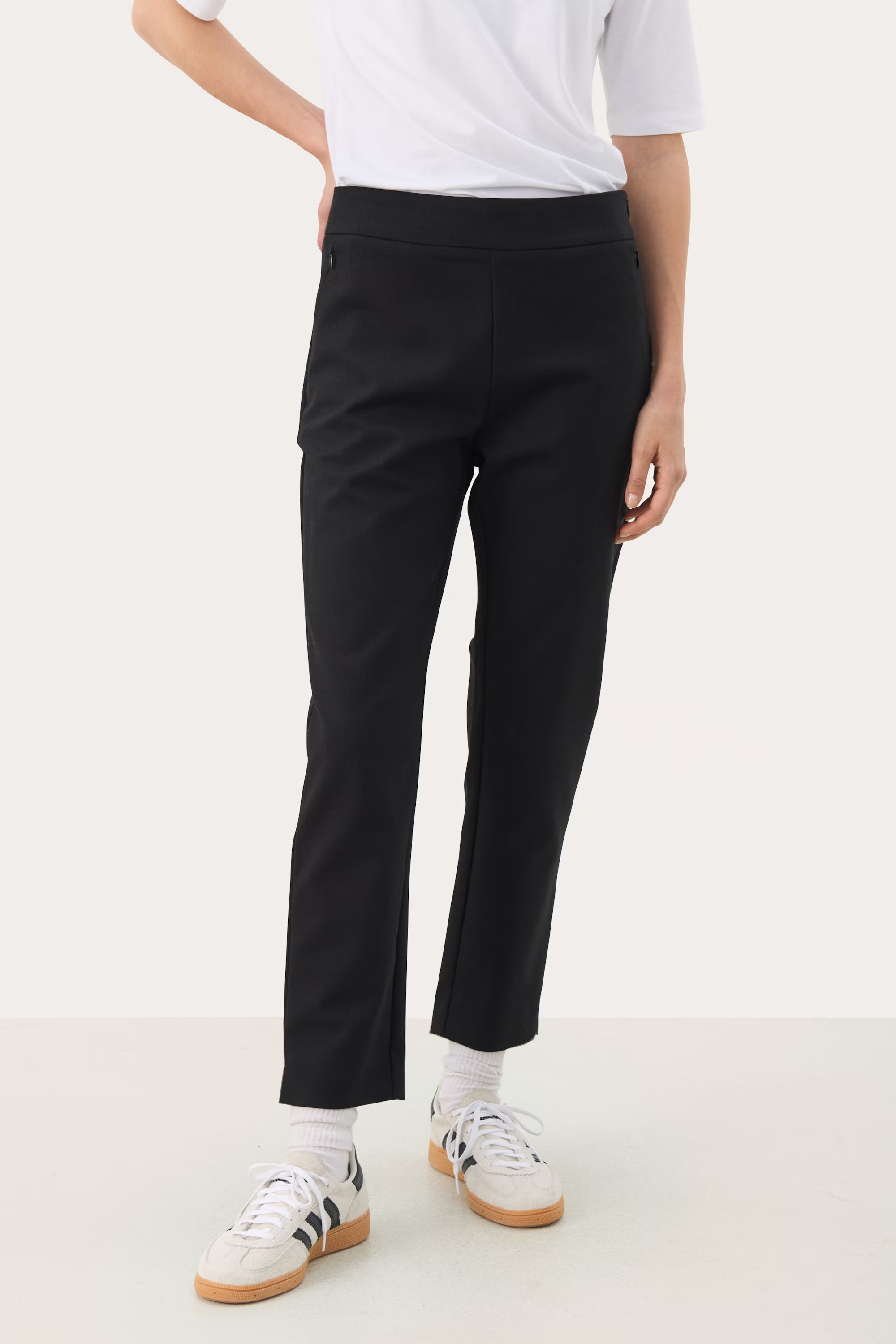 Model wearing Part Two Nyla slim fit black trousers with trainers