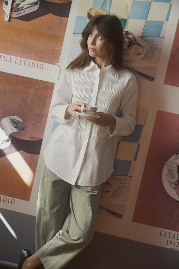 Model standing in natural light wearing longline white smocked shirt for women