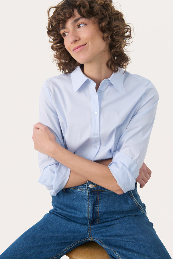 Close-up of women’s classic collar and button front on blue poplin shirt