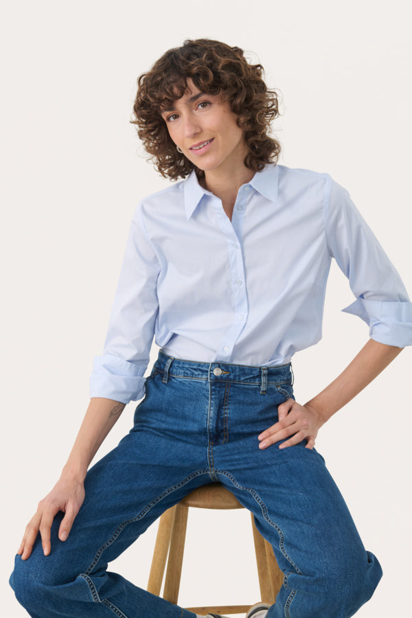 Model styling blue cotton shirt tucked into jeans for a relaxed day look