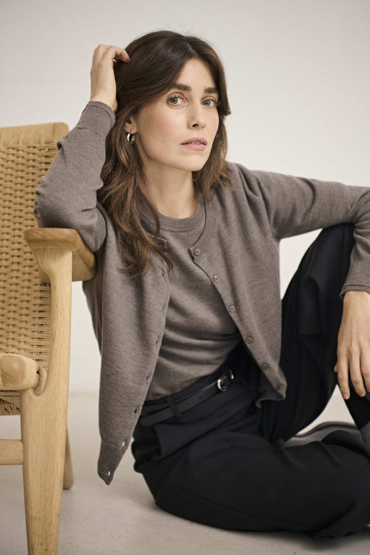 Part Two NoelaniPW brown grey wool cardigan in lifestyle shot, model seated wearing cardigan over trousers.