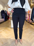 Close-up of mid-rise waistband and front pleat detail on Penny Black black tapered leg trousers