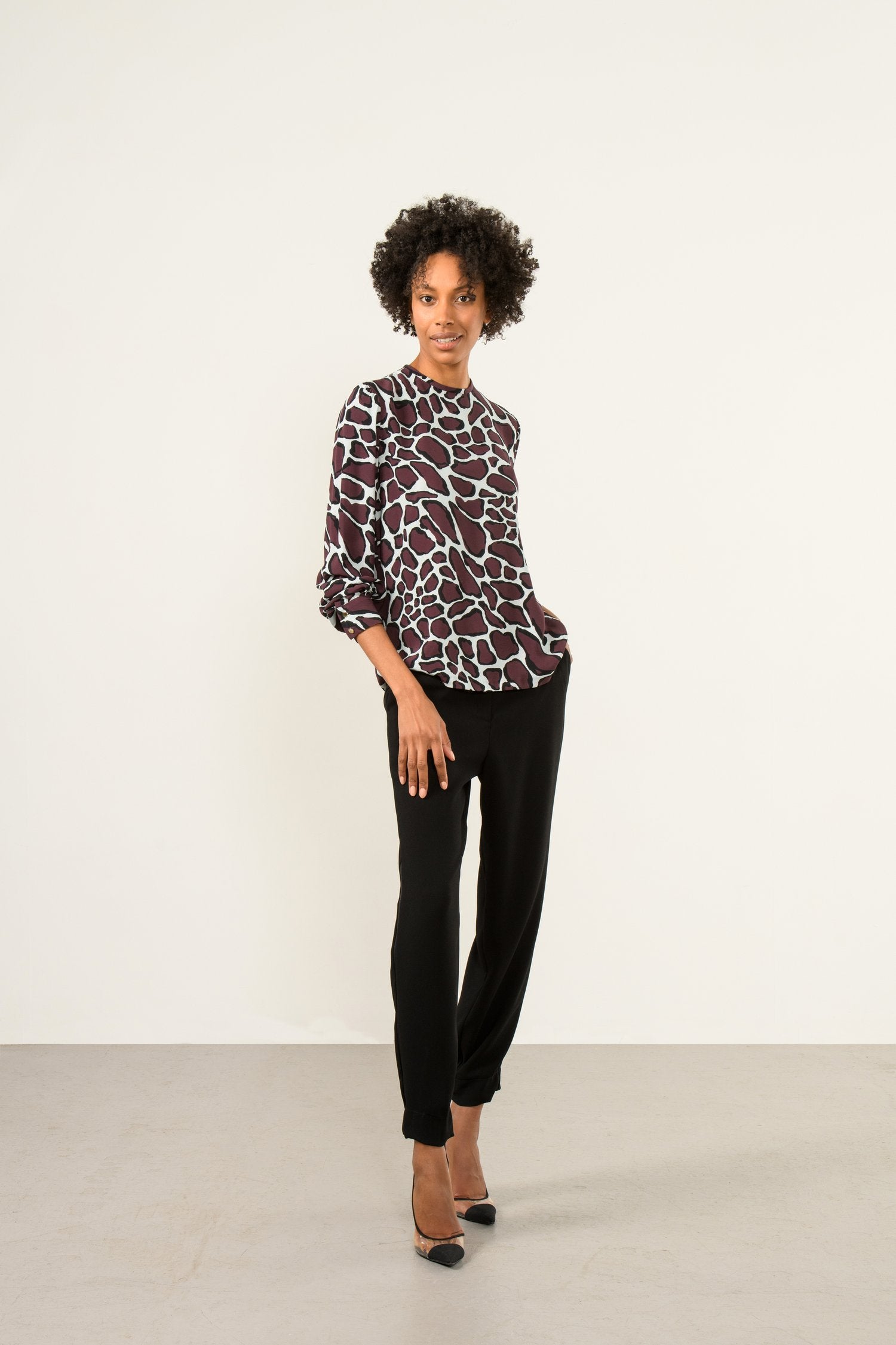 Model wearing Sisters Chantel animal print blouse front view paired with black trousers 