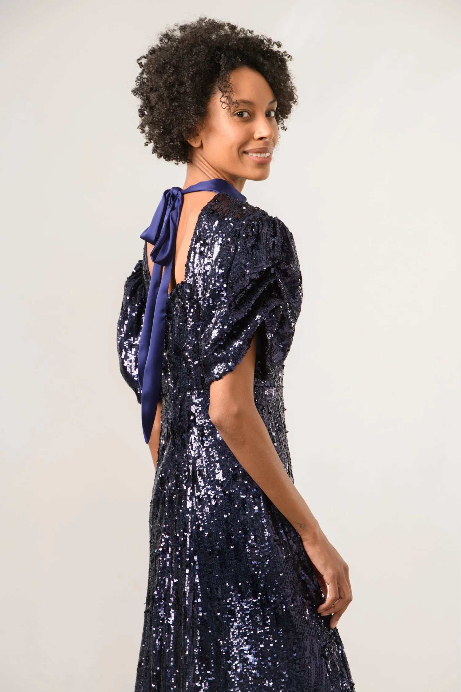Back detail of Sisters by Caroline Kilkenny navy sequin dress with blue ribbon tie and puff sleeves