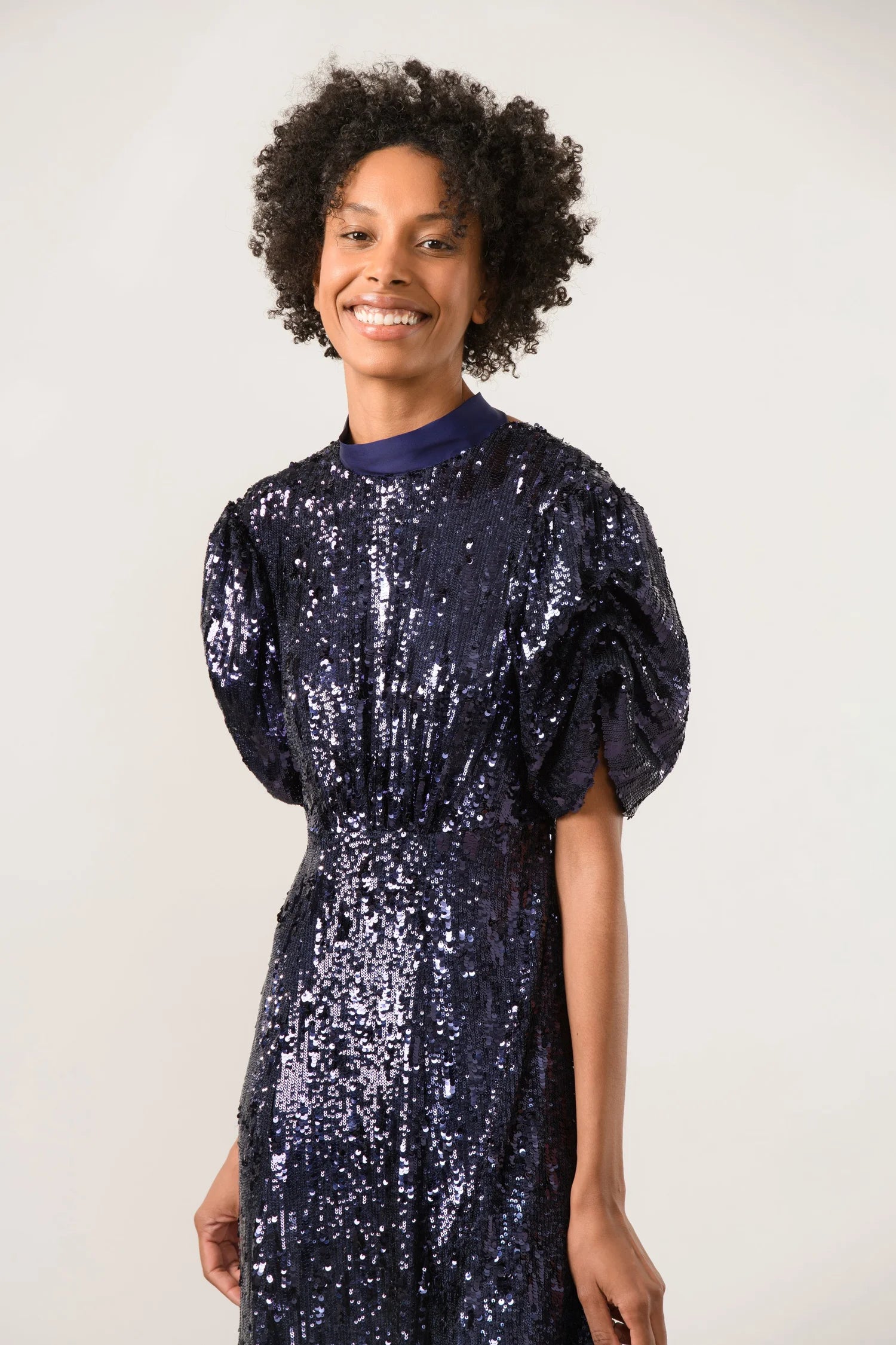 Model wearing sparkly Sisters sequin navy midi dress with structured sleeves
