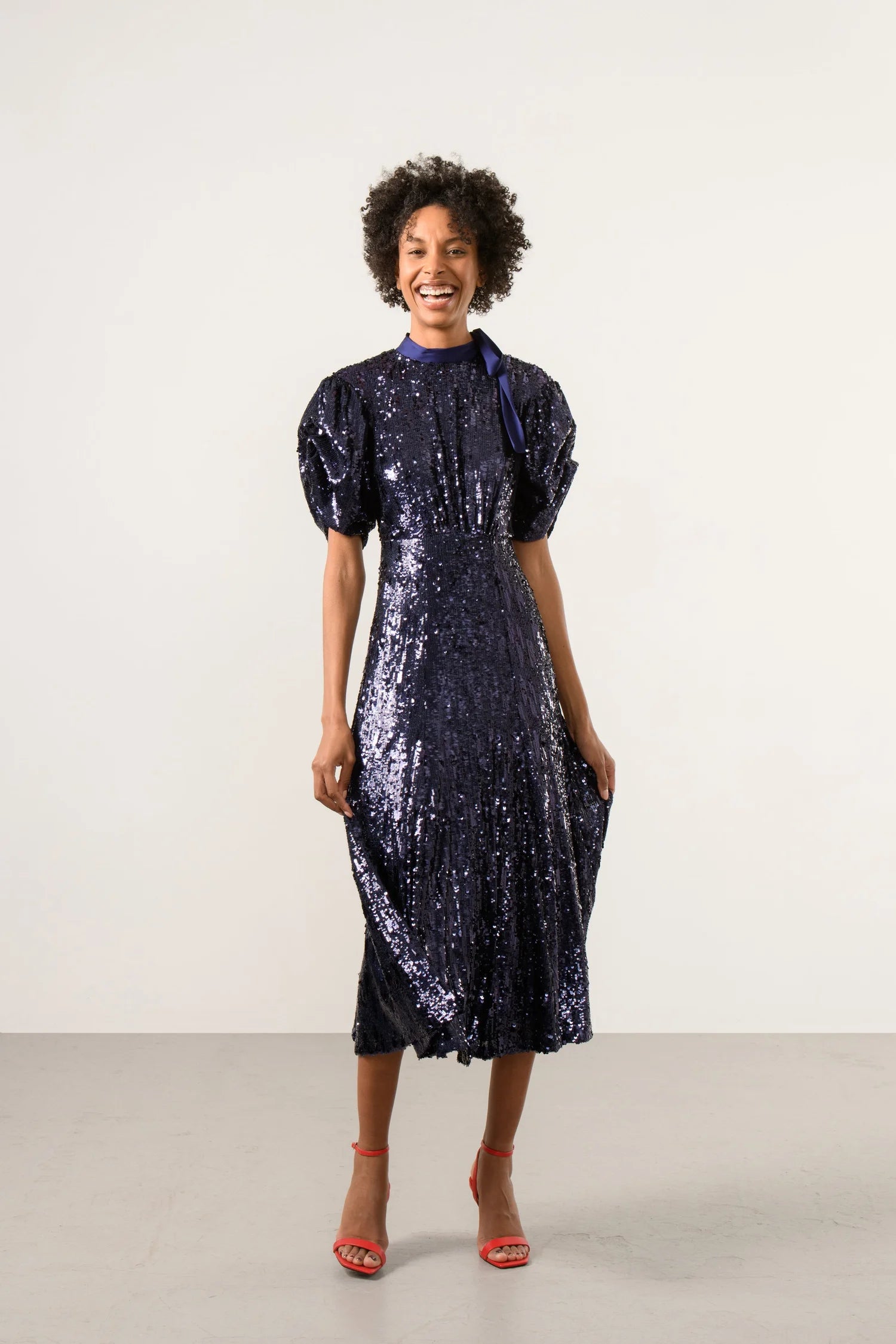 Front view of model wearing navy sequin midi dress with balloon sleeves 