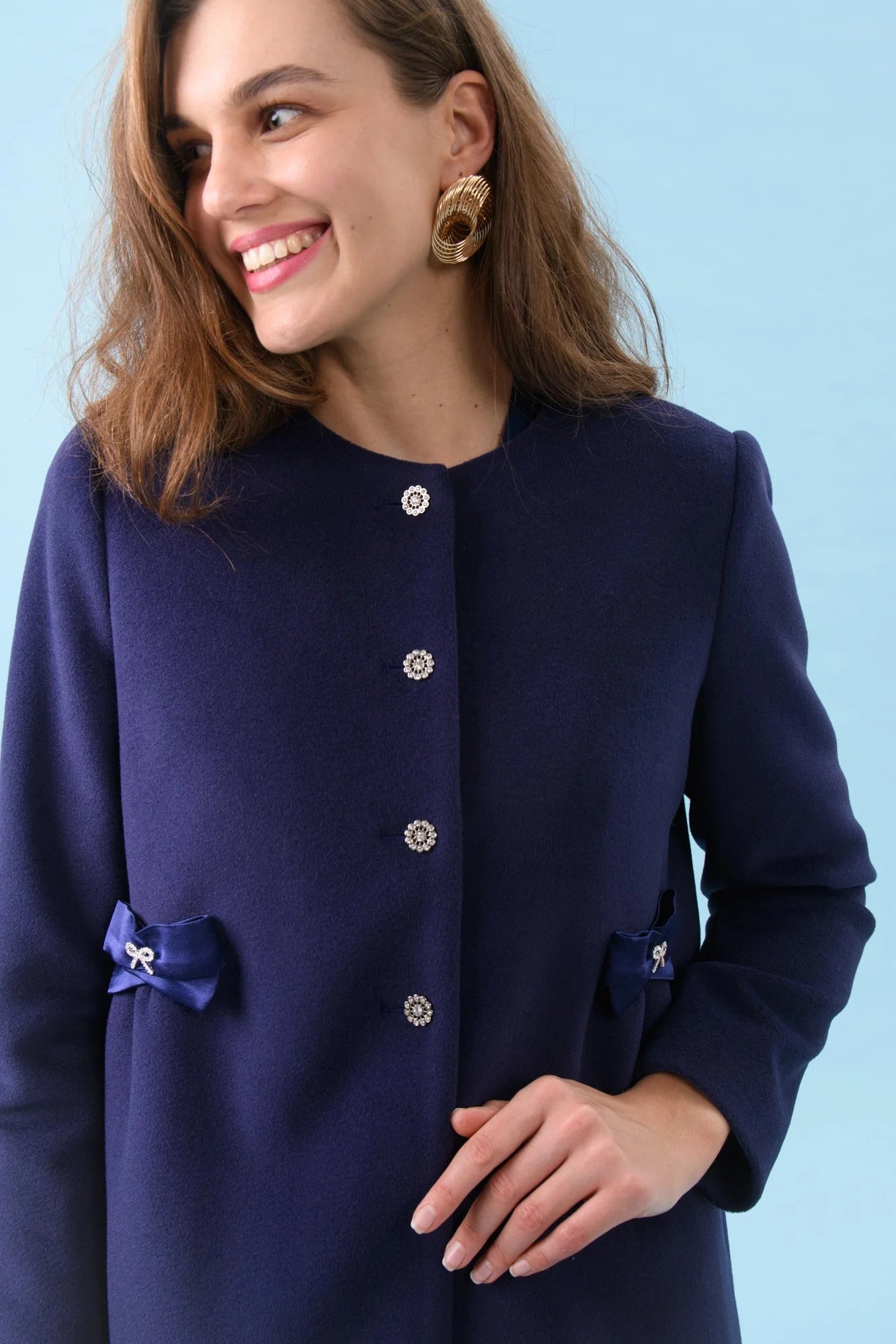 Close-up of crystal buttons and bow pocket detail on Olivia occasion coat