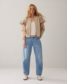 Summum bomber jacket with frill shoulder styled with blue jeans, front view